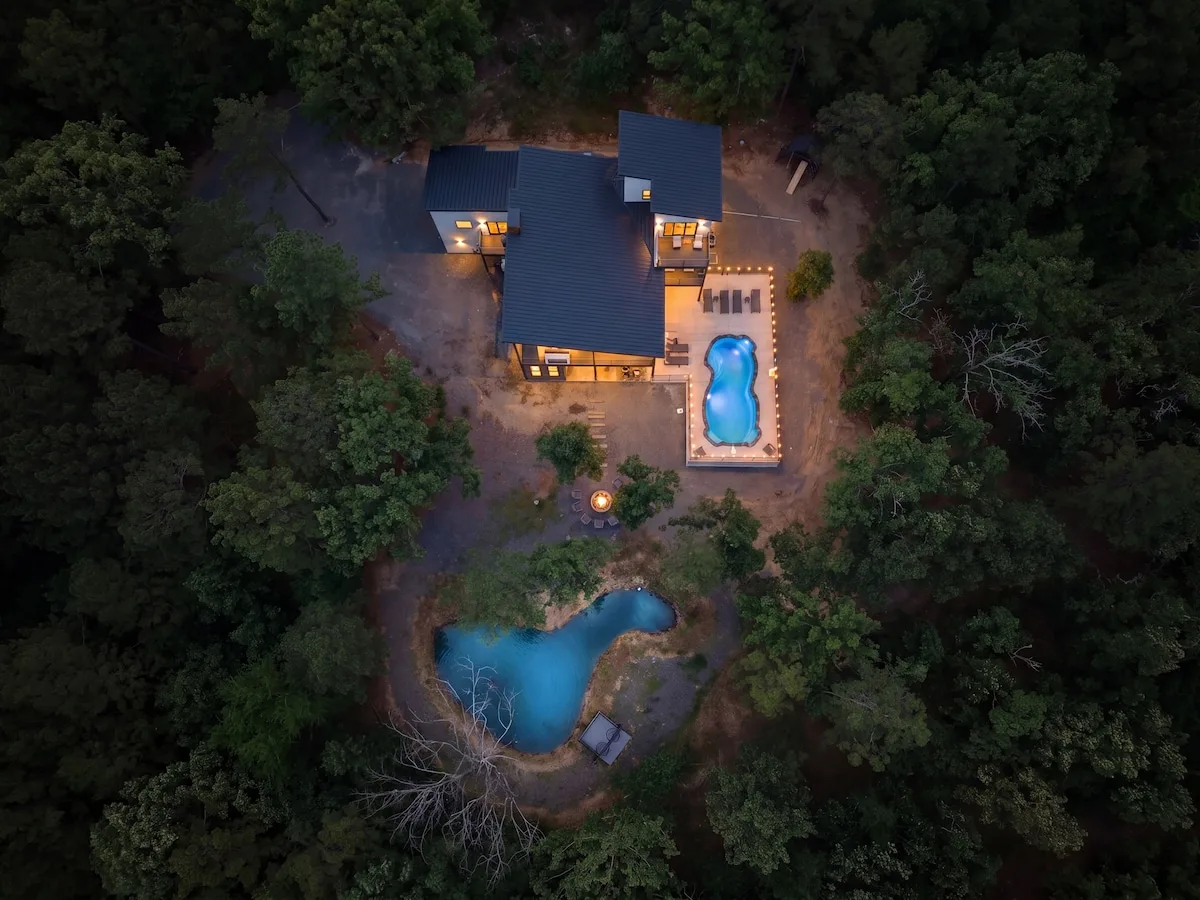 Aerial view of The Aroha, its heated pool, pond, and wooded acreage
